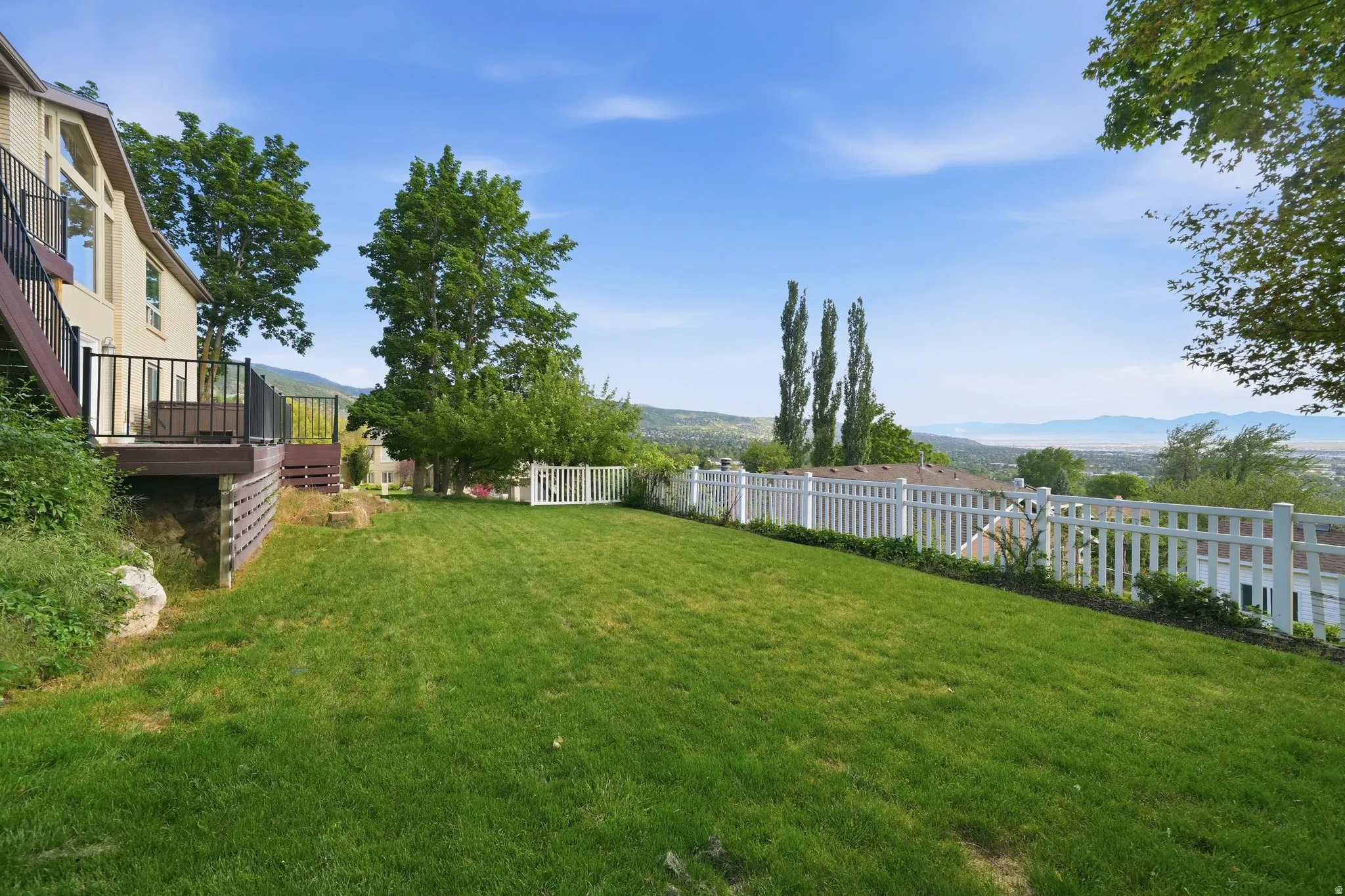 Expansive lawn area with a white picket fence bordering the property