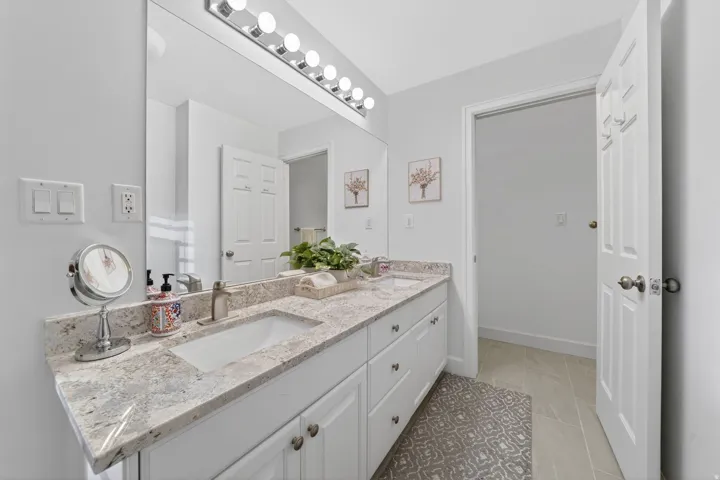 Double vanity featuring integrated sinks, light-toned countertops, and white cabinetry