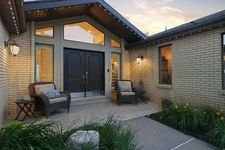 Brick exterior featuring a gabled entryway with dual black panel doors and flanking sidelights