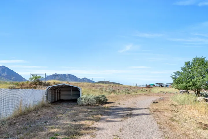 Expansive open lot featuring a clear gravel path and metal carport structure