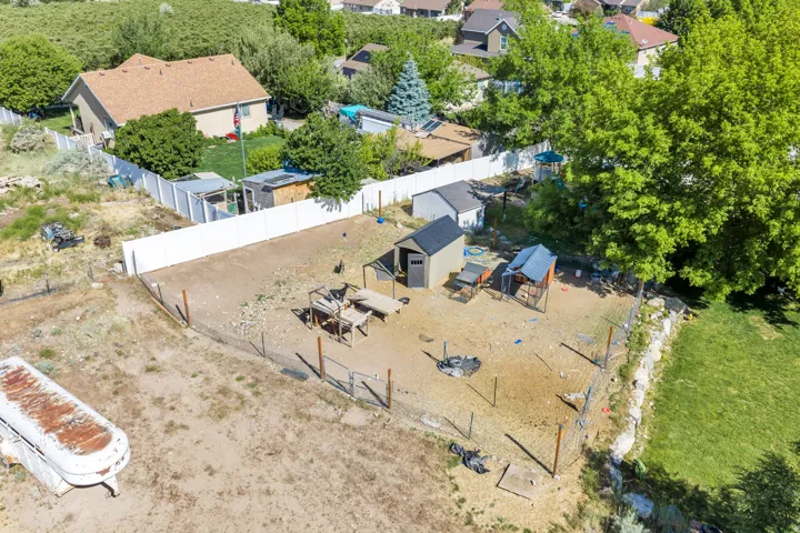 Expansive fenced yard featuring a storage shed, a secondary structure with a dark roof, and a gravel surface