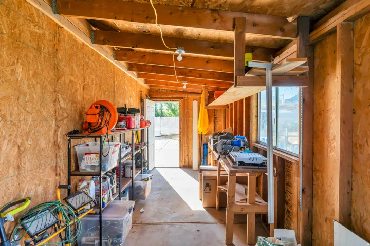 Outbuilding interior featuring exposed wood framing, oriented strand board walls, a built-in workbench, and multiple windows providing natural illumination