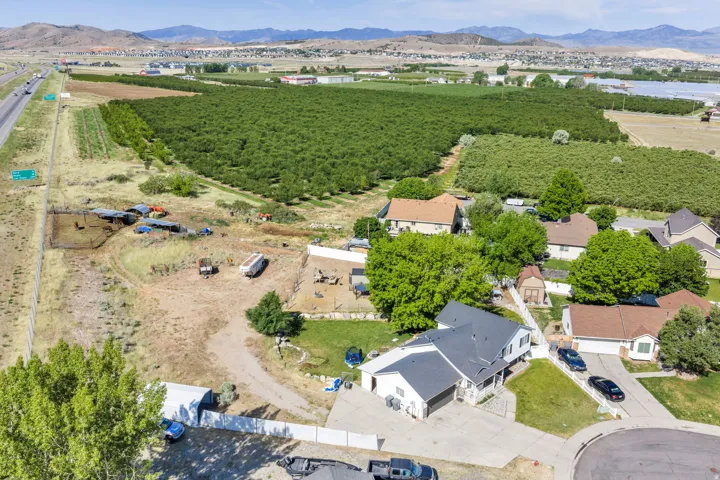 Aerial perspective showcasing expansive agricultural fields, residential properties, and distant mountains