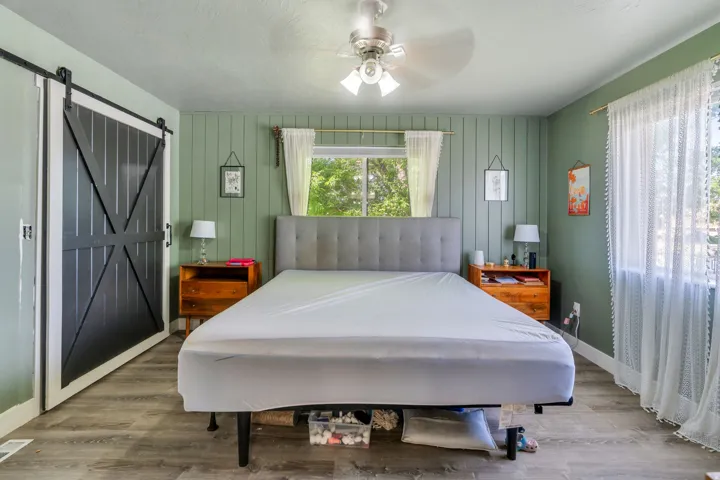 Spacious room featuring wood-finish flooring, a ceiling fan, and a large window