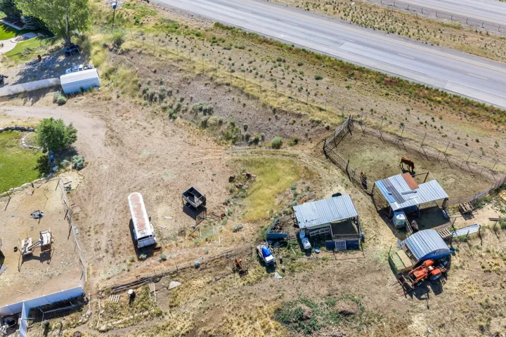 Expansive rural property featuring multiple outbuildings, fenced enclosures, and direct access to a nearby highway