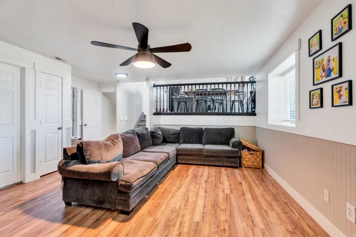 Lower-level living space featuring wood-finish flooring, a ceiling fan, and white trim