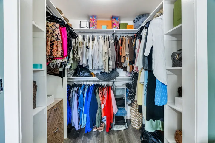Walk-in closet with built-in shelving, hanging rods, wood-finish flooring, and integrated lighting