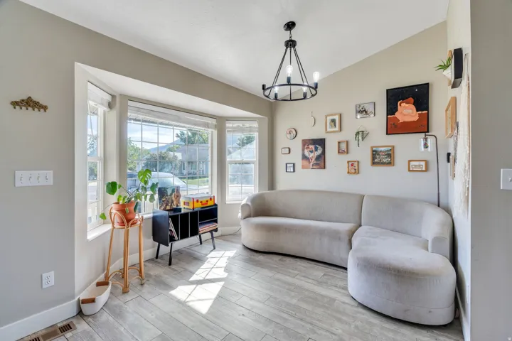 Bay window feature with multiple panes, wood-finish flooring, and a modern chandelier