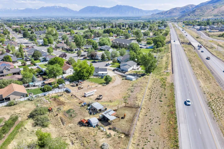 Expansive property featuring undeveloped land with outbuildings, bordered by a multi-lane highway and residential developments