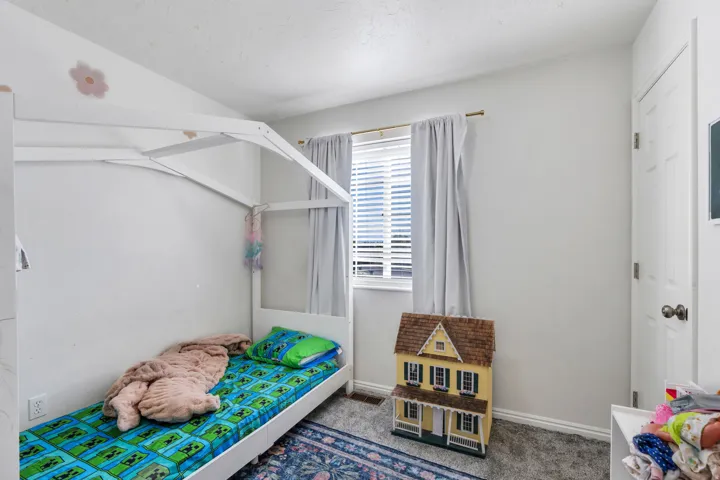 Bright interior with light gray walls and a single window featuring horizontal blinds and gray drapes