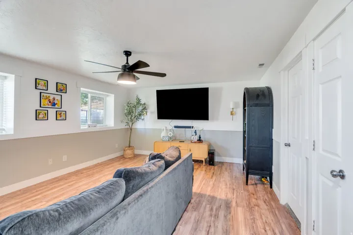 Spacious room featuring wood-finish flooring, white walls with a lower wainscoting detail, and multiple windows