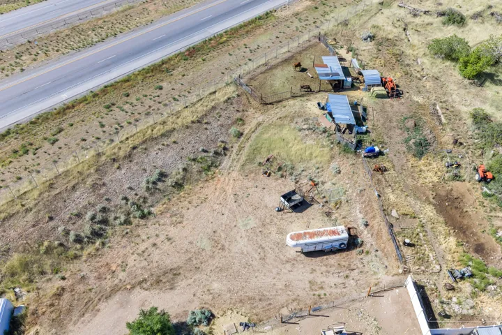 Expansive land parcel featuring open terrain and a fenced area with multiple outbuildings