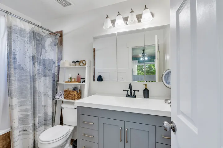 Bathroom featuring a grey vanity with a white countertop and a black faucet