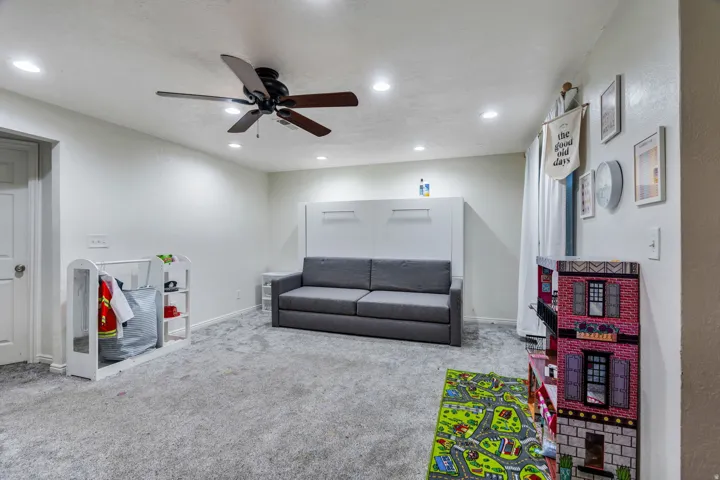 Spacious room featuring light gray carpet flooring, recessed lighting, and a ceiling fan