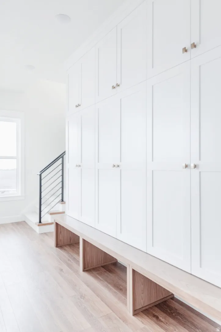 Built-in white panel cabinetry featuring brushed nickel hardware, integrated seating with light wood-finish detailing, and wood-finish flooring