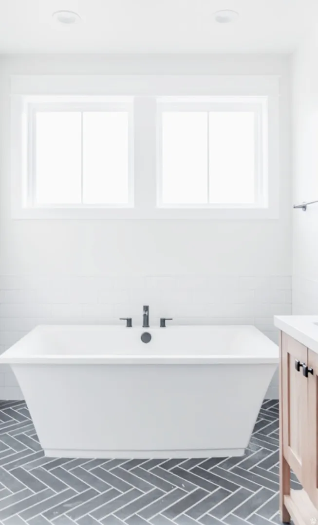 Freestanding soaking tub with matte black fixtures set against white subway tile wainscoting