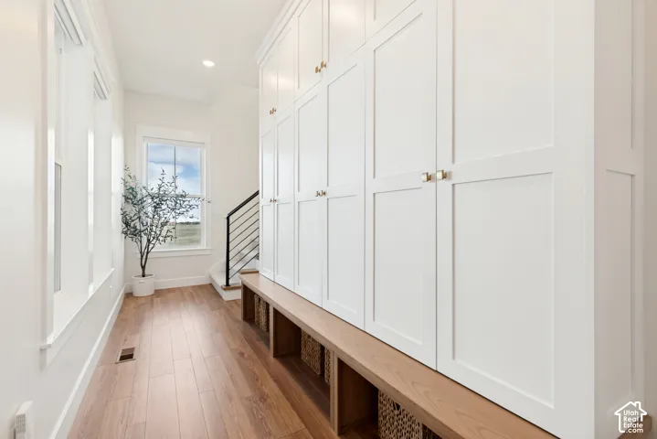 The mudroom off the garage features extensive white built-in cabinetry, large windows and bench for convenience.