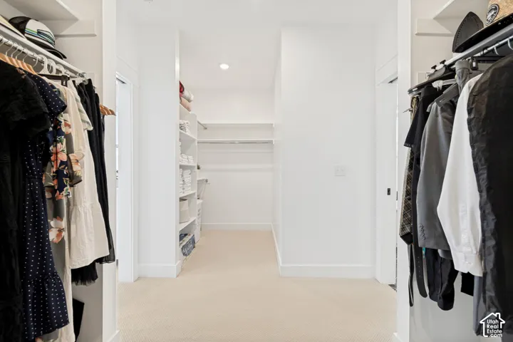 Walk-in closet with abundant storage, featuring built-in shelving, hanging rods, recessed lighting, and carpet flooring
