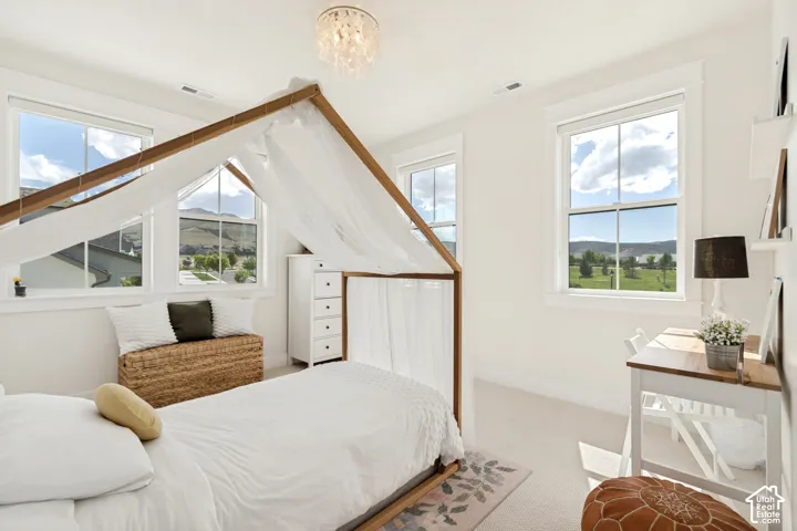 Bedroom featuring multiple double-hung windows, white trim work, and a crystal chandelier