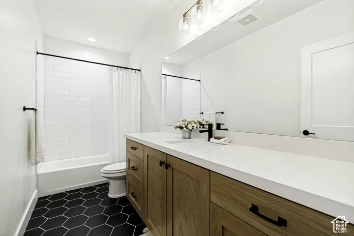 Basement bathroom featuring a light wood-finish vanity with a white countertop and black fixtures