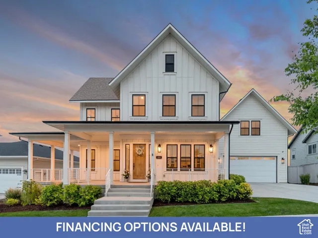 Modern farmhouse exterior featuring vertical board-and-batten siding, a covered front porch with a white railing, a wood-finish front door, multi-pane windows with black trim, and an attached multi-car garage