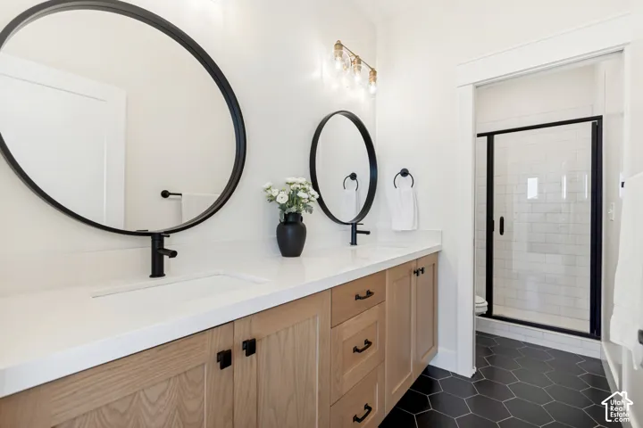 Bathroom featuring a dual vanity with light wood-finish cabinetry and white countertops