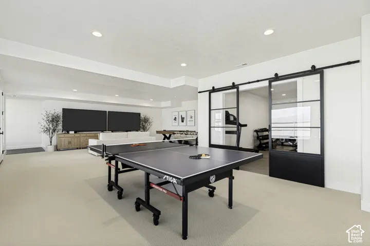 Expansive room featuring recessed lighting, light-colored carpet flooring, and a media wall