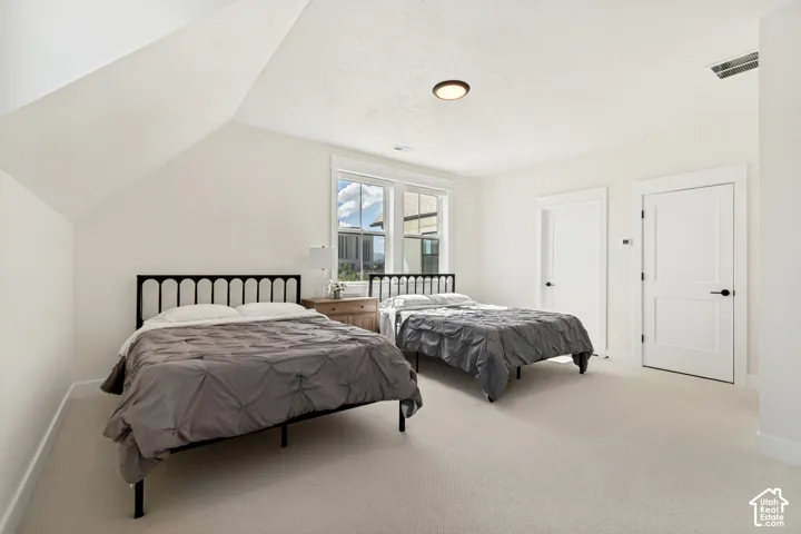 Generous guest loft bedroom with sloped ceilings and two white paneled doors