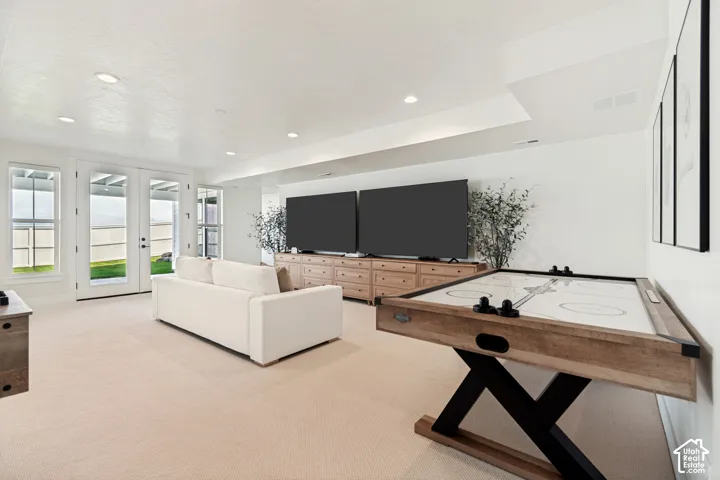 Spacious recreation room featuring recessed lighting, light-toned carpeting, and a rear wall with multiple windows and a double-door exterior entry