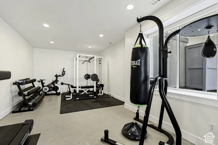 Dedicated fitness space featuring light-colored flooring, recessed lighting, and a prominent window