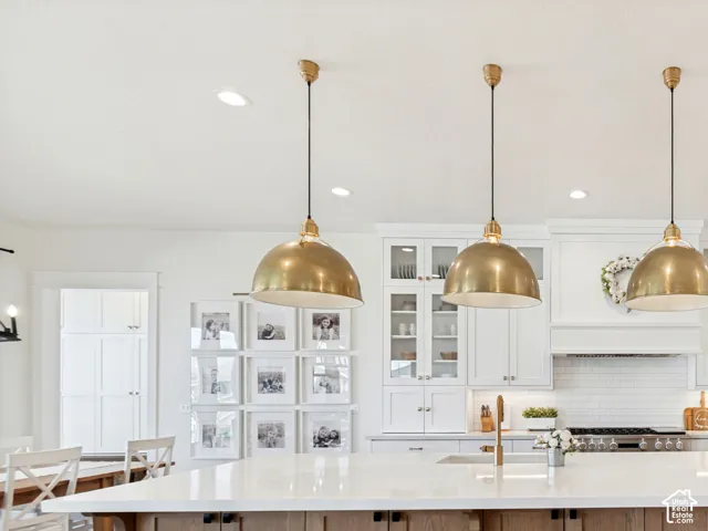 Spacious kitchen featuring a large central island with seating, white shaker cabinetry, stainless steel appliances, and wood-finish flooring