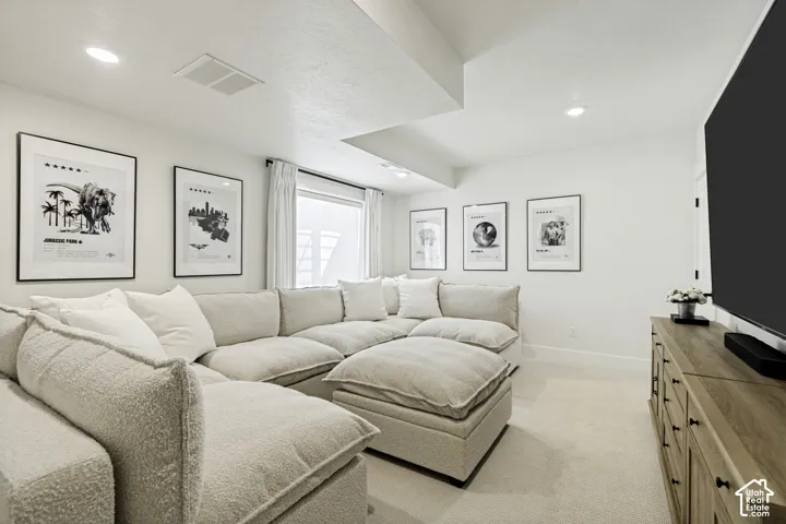 Media room featuring light-toned carpet flooring, recessed lighting, a window with white drapes, and a wood-finish media console