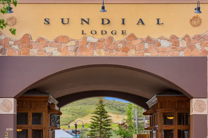 Archway entrance featuring a stone facade with integrated signage, decorative sconces, and carved wood architectural details