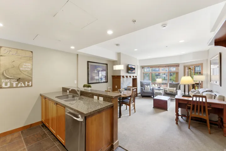 Open-concept living area featuring a kitchen island with dual sinks and stainless steel appliances, a dining space, and a living room with an integrated television