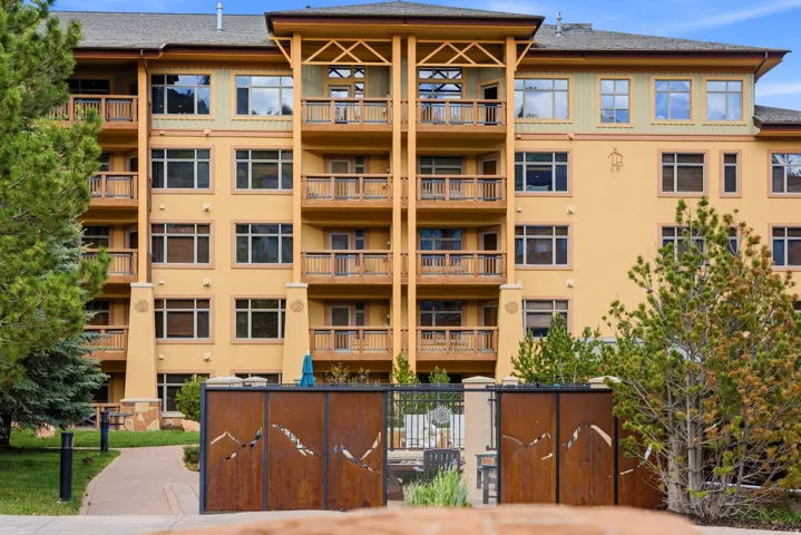 Multi-level architectural building featuring numerous private balconies with wood railings, a stucco exterior, and extensive windowing