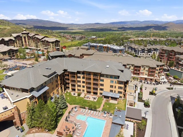 Contemporary multi-story building featuring multiple balconies, a ground-level swimming pool, and a spa