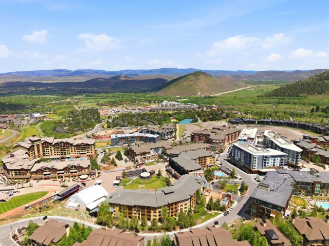 Expansive aerial perspective showcasing a vibrant community nestled within a mountainous, verdant landscape