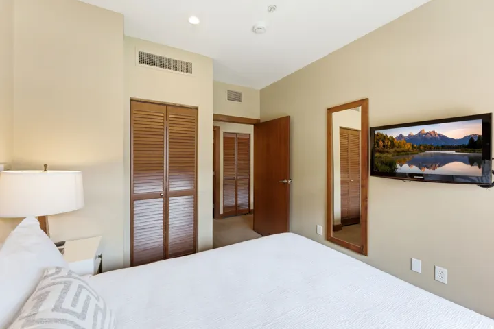 Bedroom featuring neutral wall paint, recessed ceiling lighting, a wall-mounted flat-screen television, and a full-length framed mirror