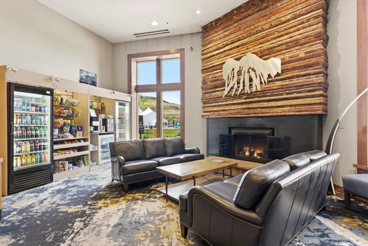 Spacious common area featuring a striking wood panel fireplace, high ceilings, large window with outdoor visibility, and a built-in refreshment station