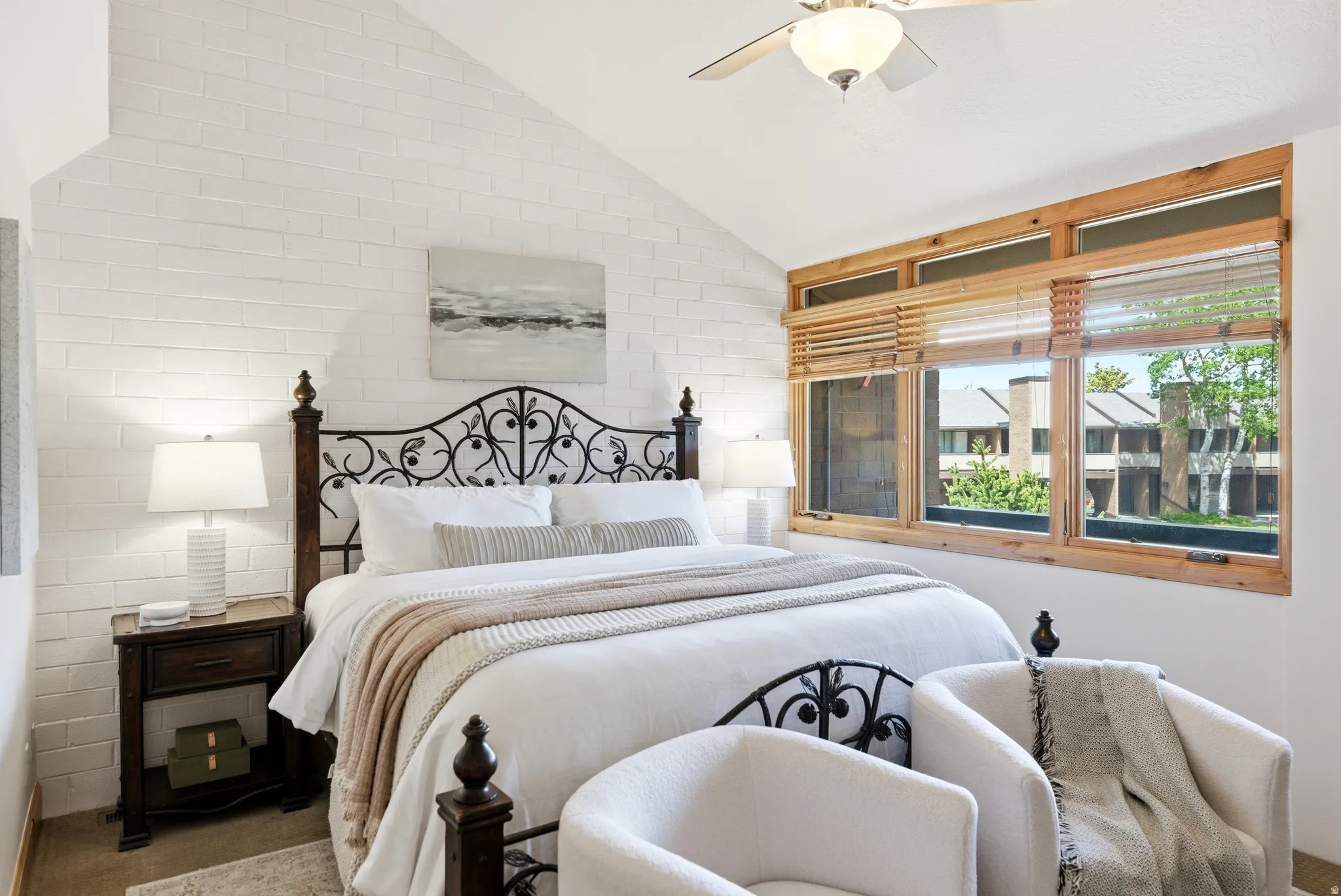Vaulted ceiling bedroom with a prominent white painted brick accent wall