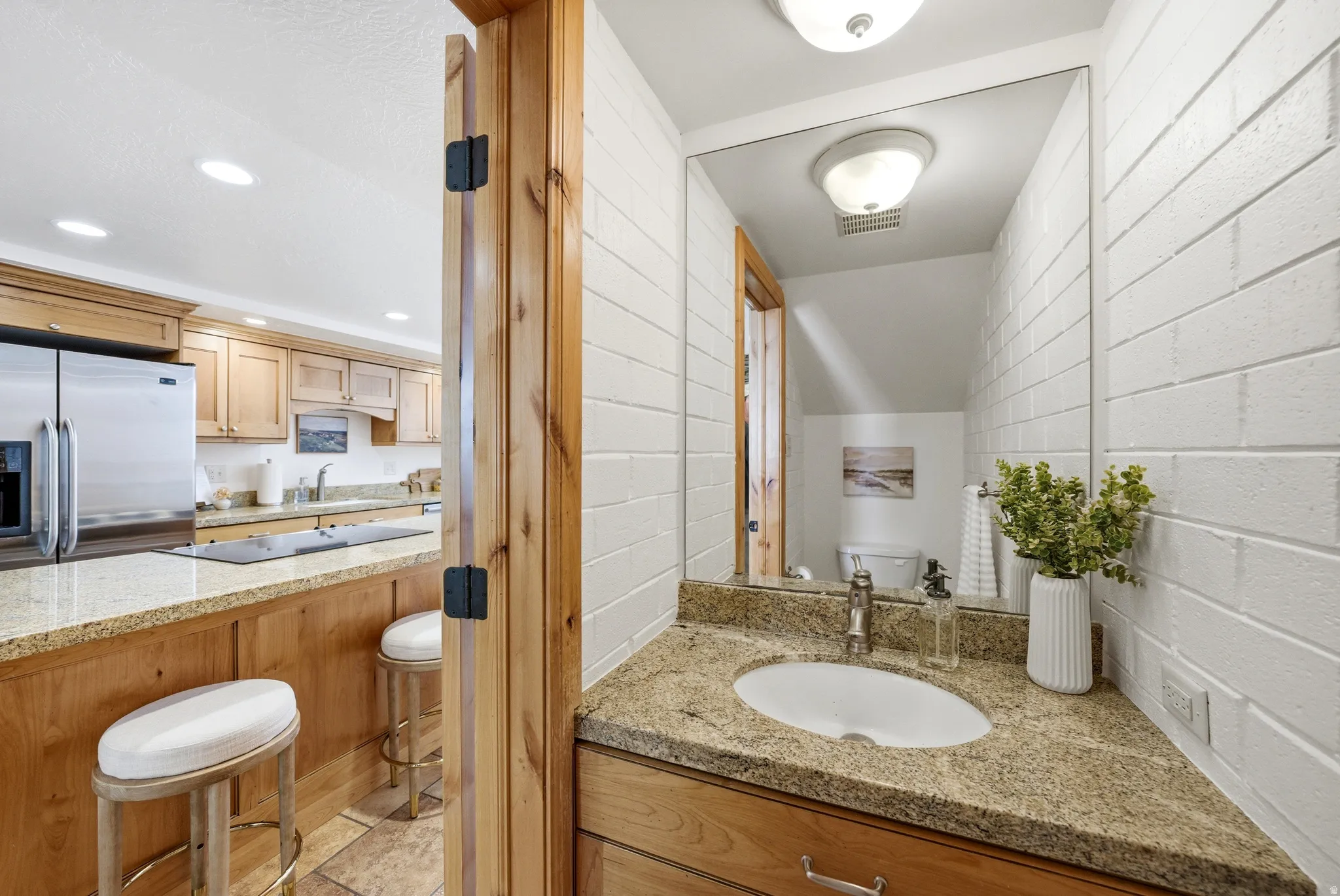 Powder room featuring a corner vanity with a granite countertop, undermount sink, and a large wall-mounted mirror