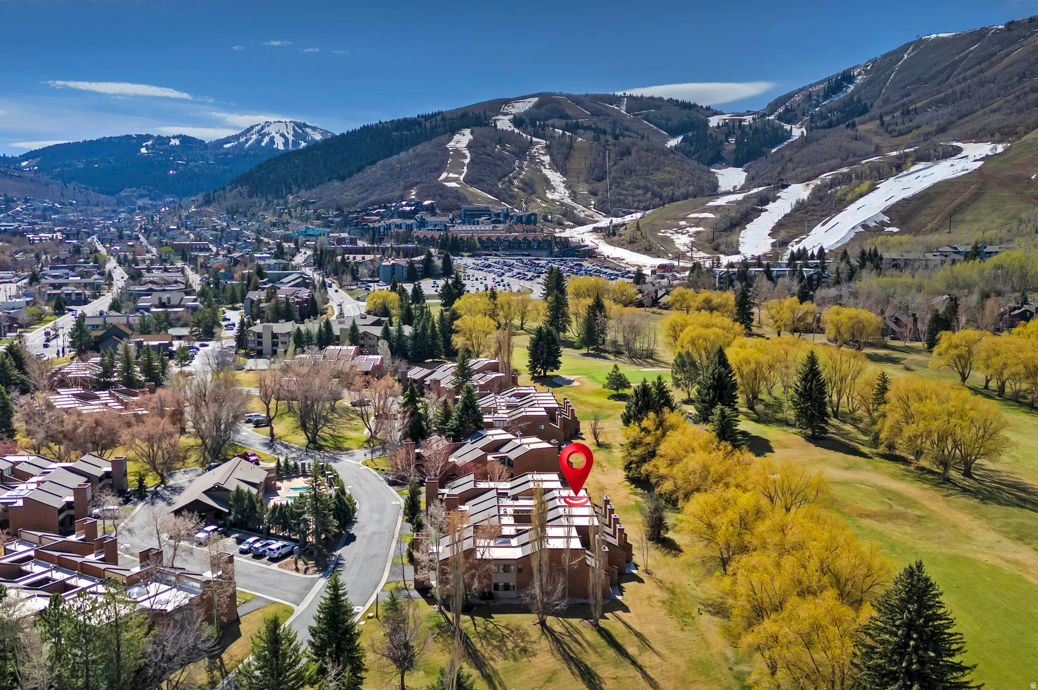 Terraced multi-story property situated alongside a golf course, featuring a gabled roofline and multiple balconies