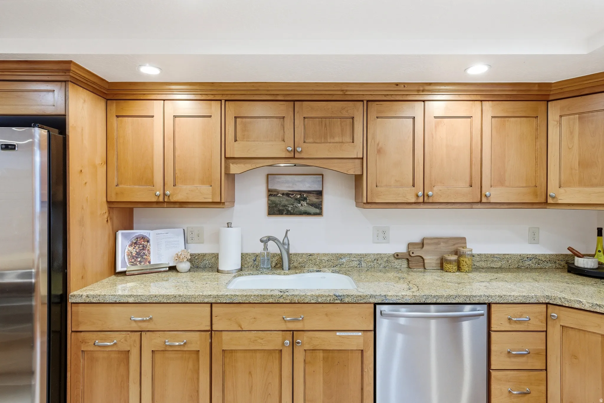 Kitchen featuring light wood cabinetry, stone-finish countertops, and stainless steel appliances