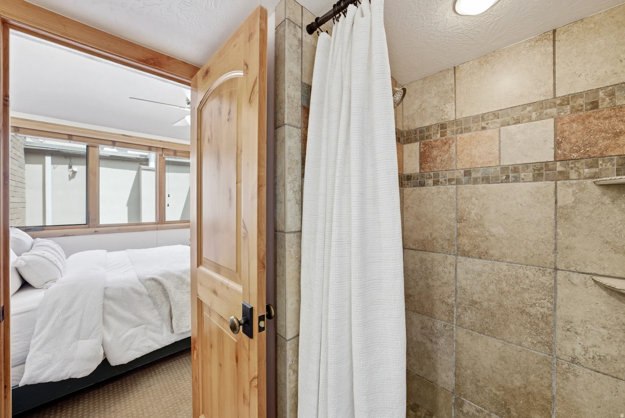 Tiled shower enclosure featuring a decorative mosaic border and built-in shelving