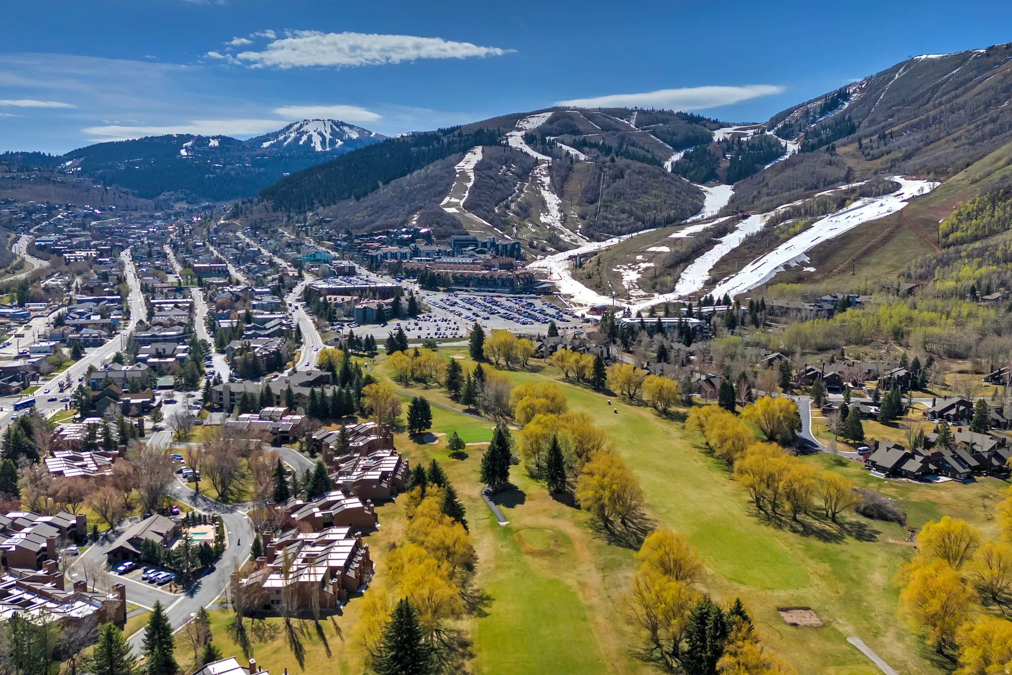 Expansive aerial encompassing a townscape, a golf course, and mountain terrain