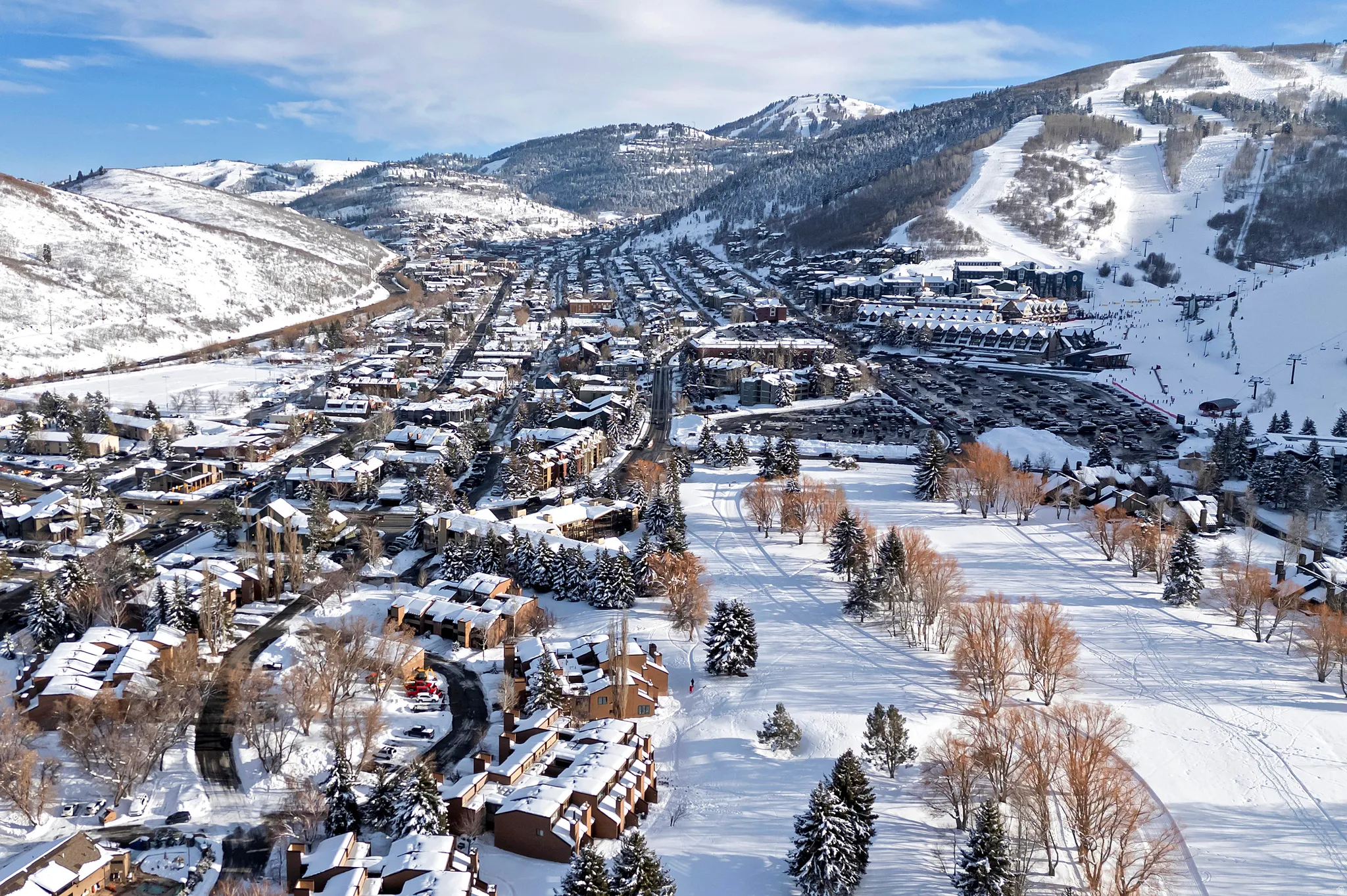 Expansive winter landscape featuring a snow-covered mountain valley with a town nestled within