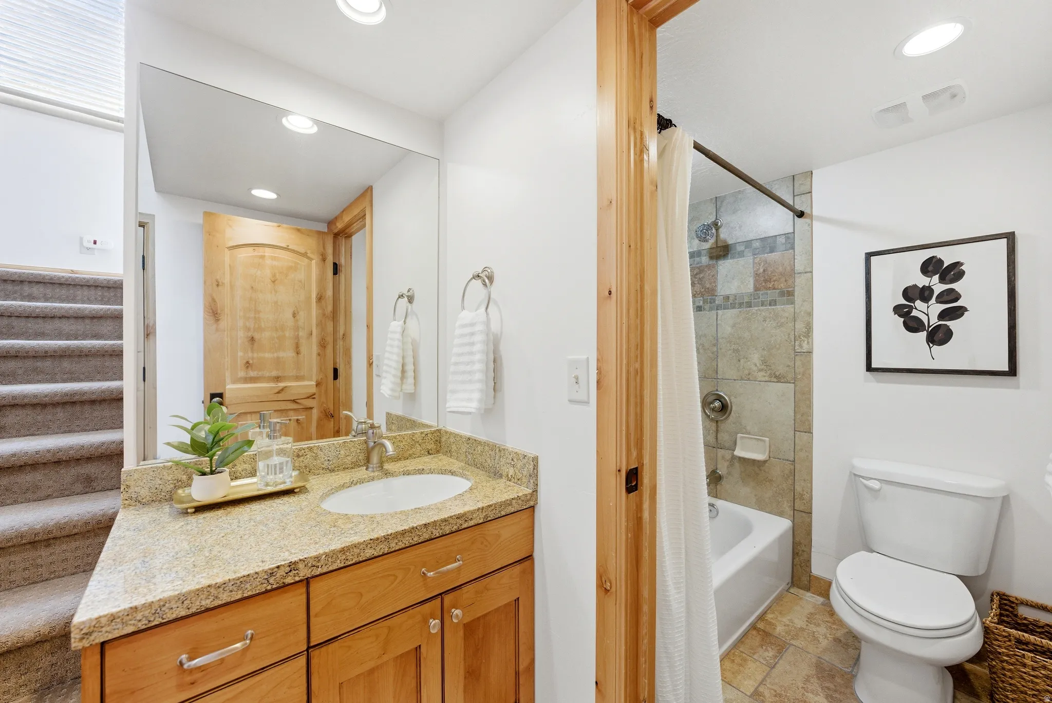 Bathroom vanity featuring a light granite countertop with an undermount sink