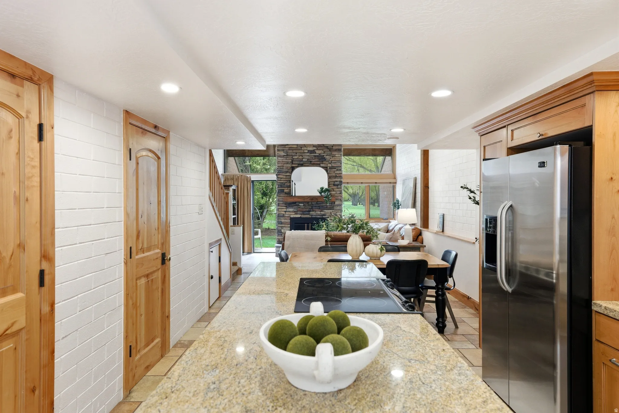 Kitchen island featuring a built-in cooktop and granite countertop, with stainless steel refrigerator and wood cabinetry