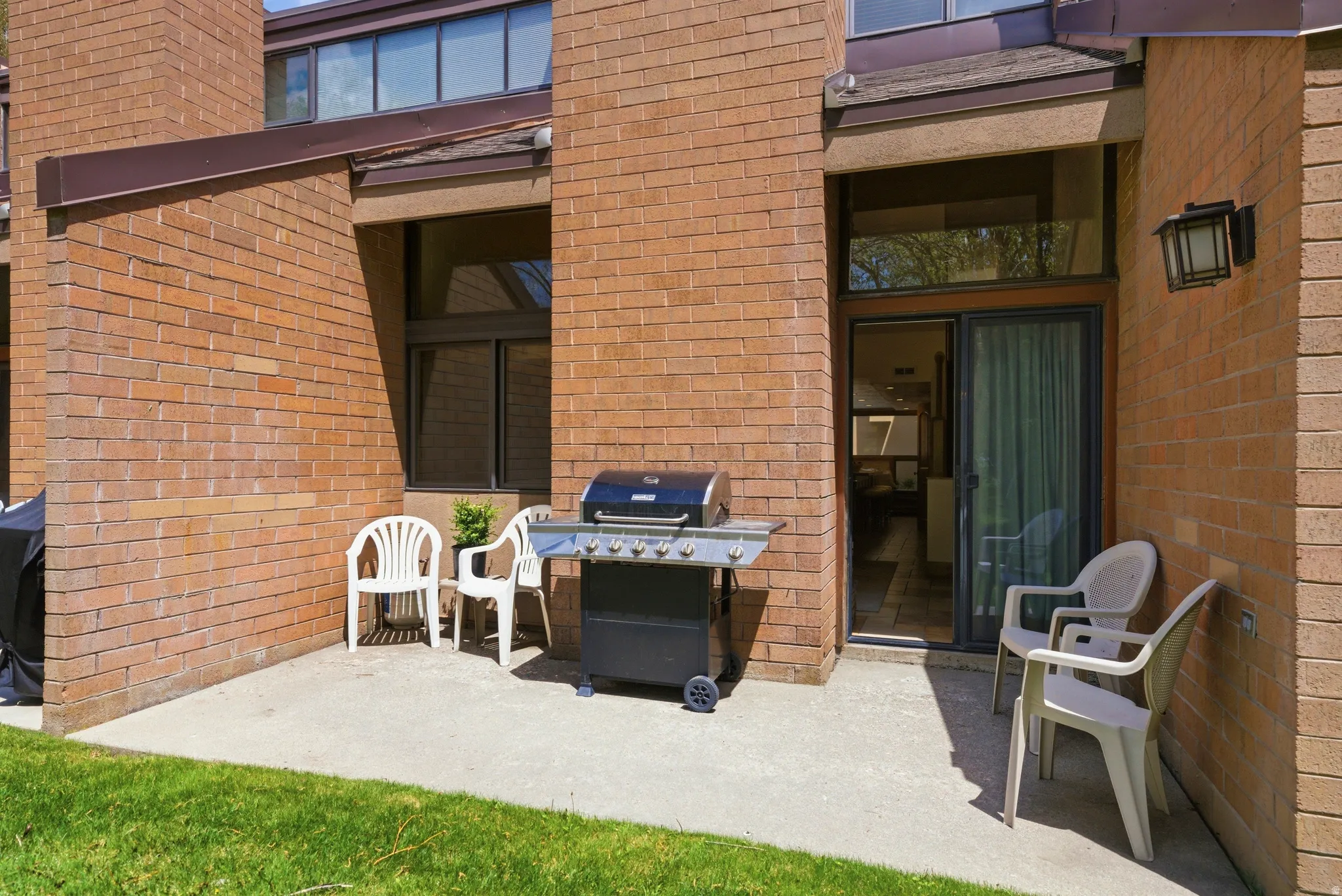 Exterior patio featuring a concrete surface, brick facade, and a sliding glass door entry