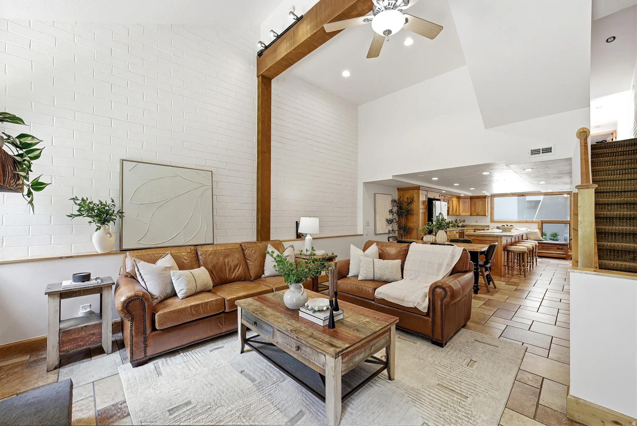 Vaulted ceiling living space featuring a white brick accent wall and exposed wood beam